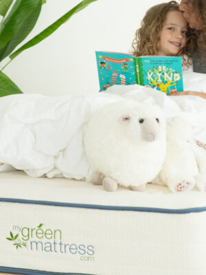 mom and daughter sitting on organic mattress with book and toys