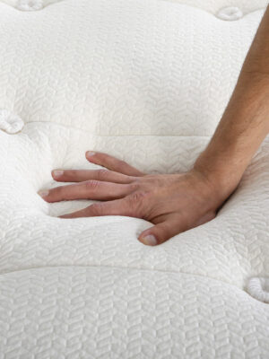 person pressing hand down on quilted organic mattress