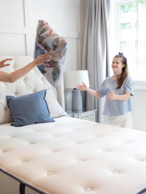 two women playing catch with a pillow over a mattress