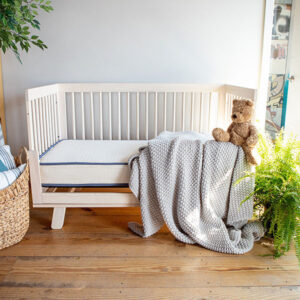 Emily Organic Crib Mattress in a natural wood crib with organic cotton bedding and teddy bear