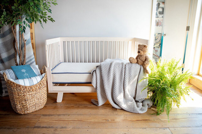 Emily Organic Crib Mattress in a natural wood crib with organic cotton bedding and teddy bear
