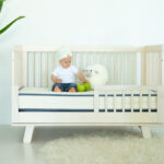 Emily organic crib mattress in wooden crib with baby
