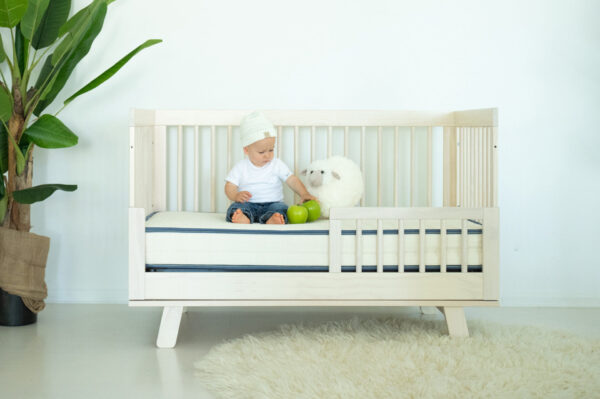 Emily organic crib mattress in wooden crib with baby