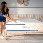 Woman placing organic cotton mattress protector on bed