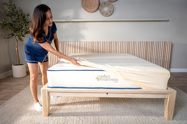 Woman placing organic cotton mattress protector on bed