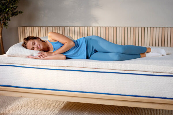 Woman lying on bed with organic latex topper and pillow set on bed for added comfort