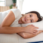 Woman resting on charcoal-infused latex pillow for cooling comfort and pressure relief