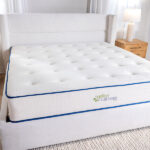 Natural Escape organic mattress displayed on bed frame in bright bedroom beside two night stands