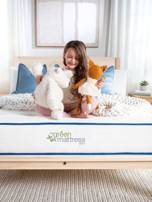 child sitting on mattress with toys