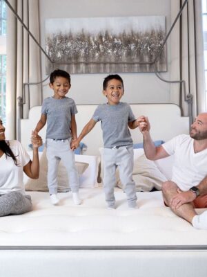 family with kids sitting on bed