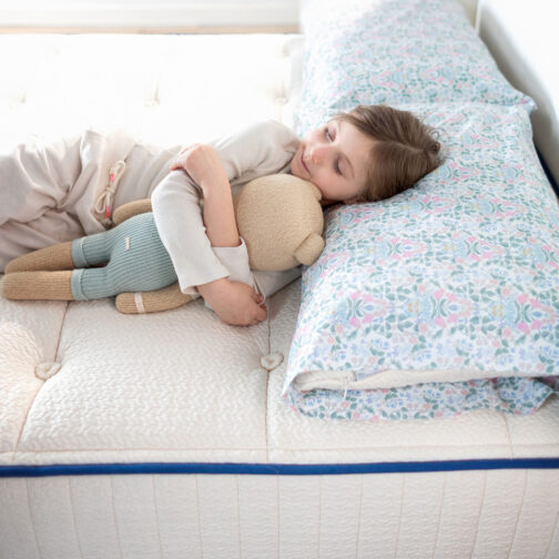 A child resting on the Pure Eco Organic Kids Mattress, showing its breathable organic cotton and wool cover designed to keep young sleepers cool and comfortable.