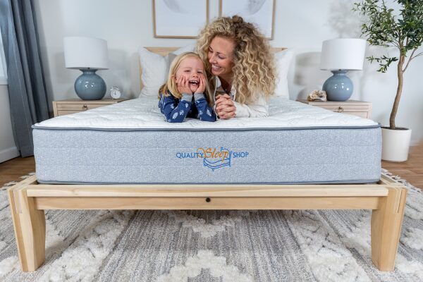 Mother and child smiling on a Quality Sleep Shop mattress, showcasing locally made comfort and durability.