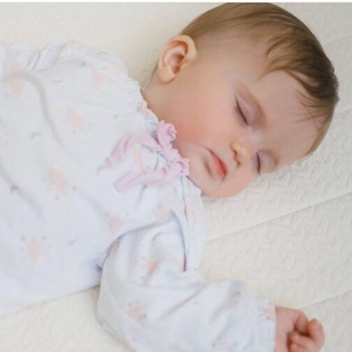 Baby sleeping peacefully on the Emily Organic Crib Mattress made with non-toxic, allergen-resistant organic materials.