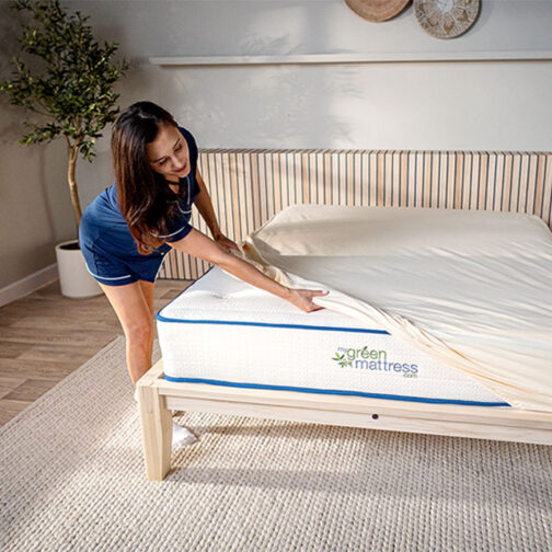 Woman putting on a mattress protector on a Kiwi Organic Mattress