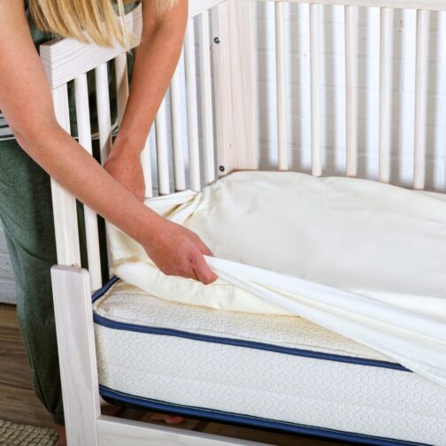 Parent adding a mattress protector to the Emily Organic Crib Mattress to keep the organic cotton cover clean and dry.