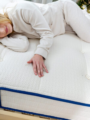 Woman lying on mattress feeling surface with hand