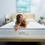 Woman sitting on Kiwi Organic Mattress and premium wood bed frame by My Green Mattress